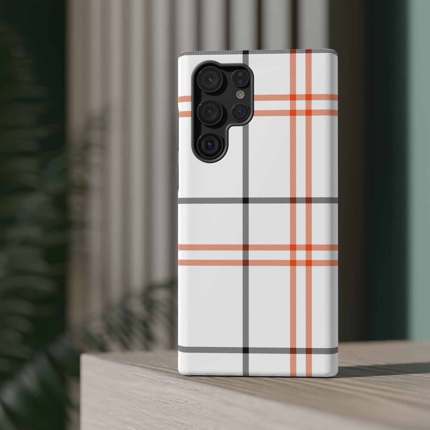 A phone case with a fall tartan plaid pattern in white and orange stripes, featuring a camera module in the center.