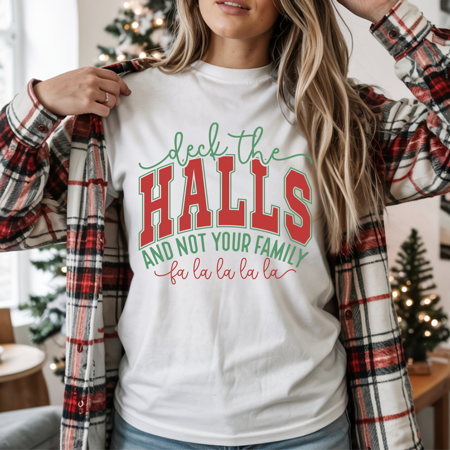 Person wearing a white t-shirt with Christmas-themed text in a festive indoor setting.